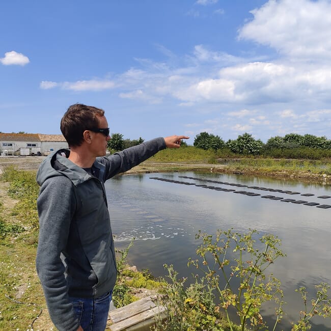 A man pointing at a pond.