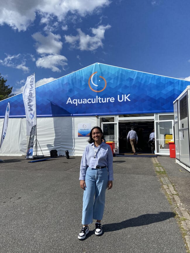 A woman standing in front of a large marquee.