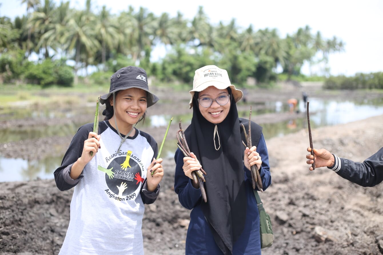 Two people holding small seedlings.