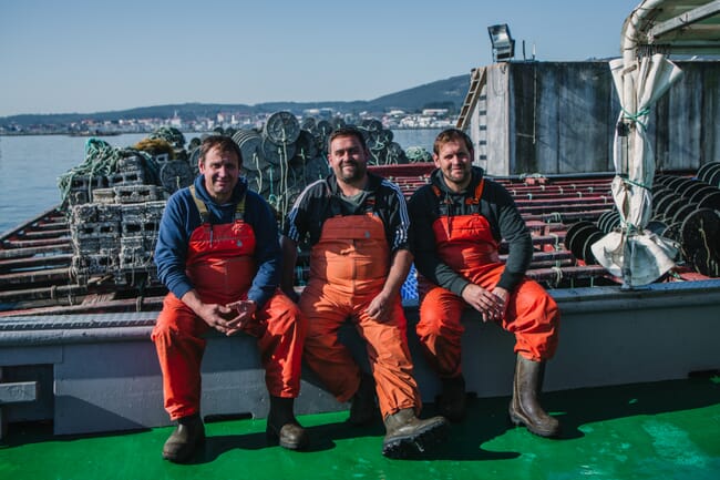 Three men sitting on a dock.