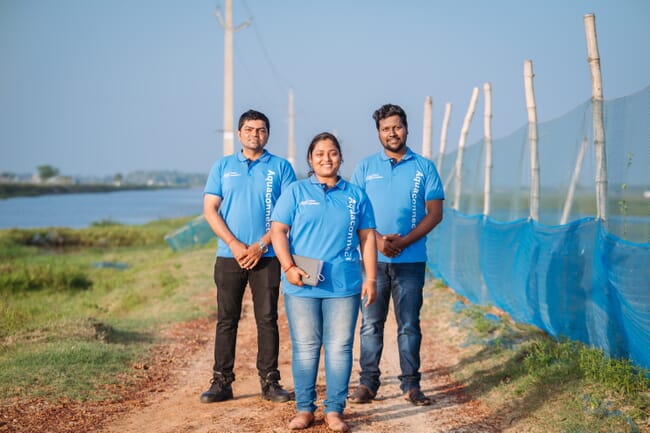 Woman and two men standing near a pond