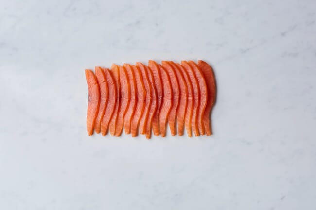 sliced salmon fillets lie on a white marble drop