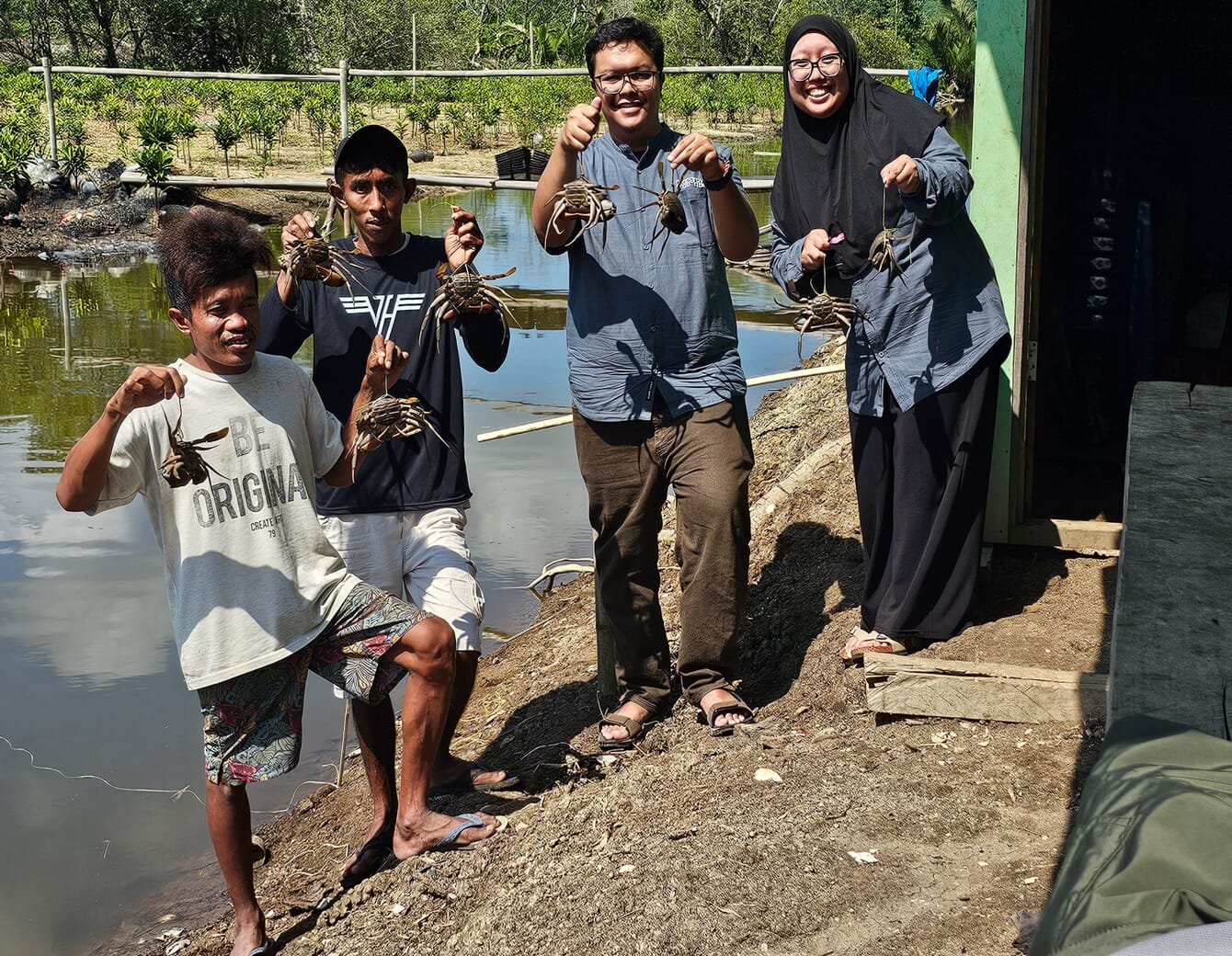 Four people holding crabs.