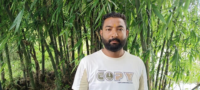A man standing in front of a large plant.