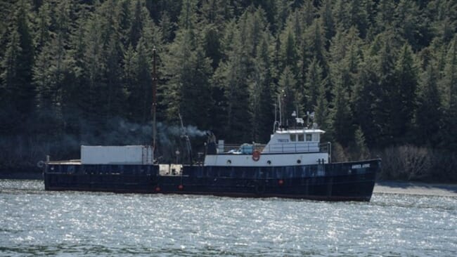 A fishing boat towing a barge.