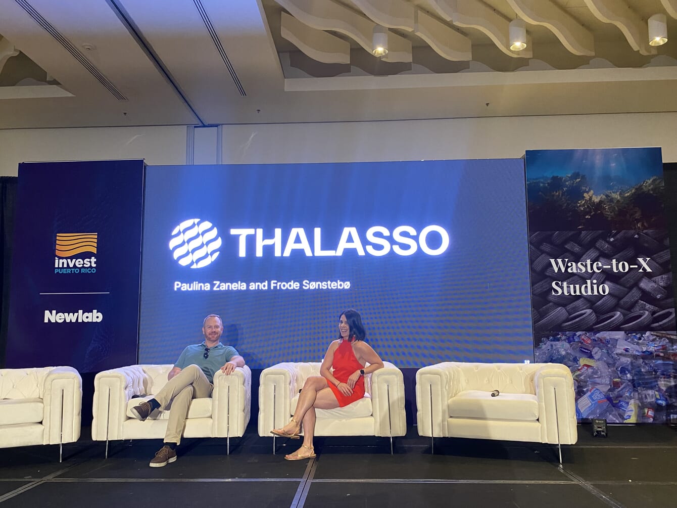 Two people sitting on a stage at an event.