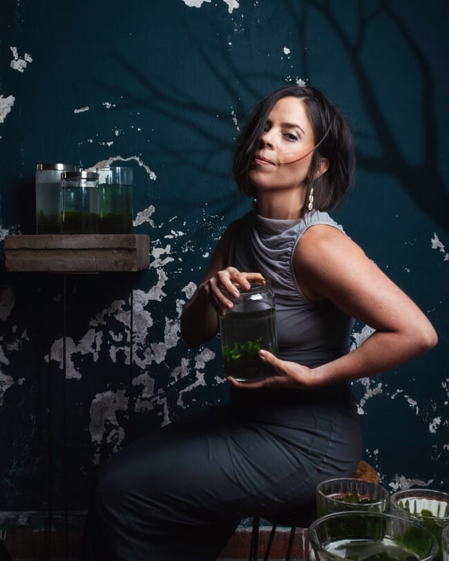 A lady in a dress holding a jar.