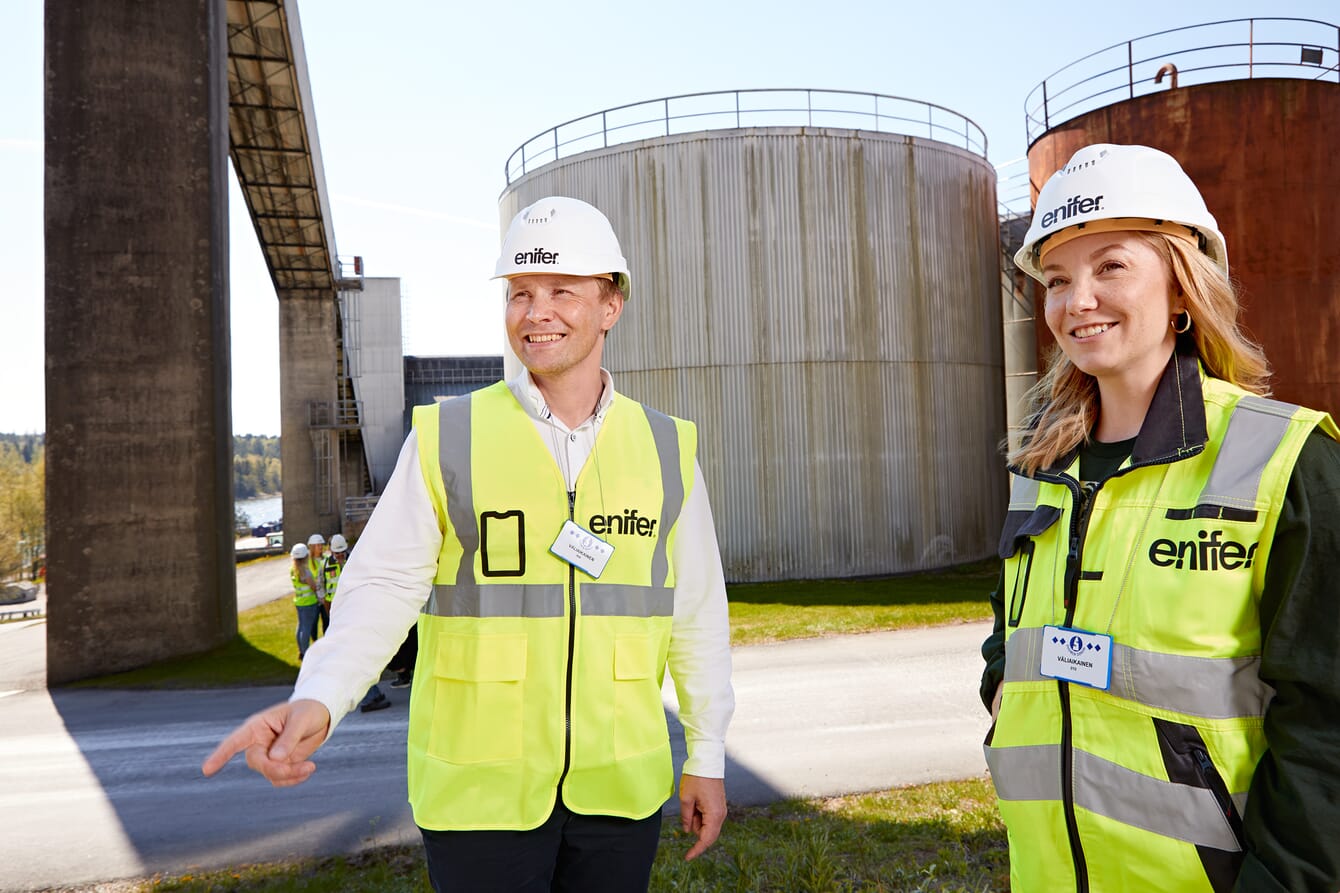 A man and a woman in hard hats outside a factory.