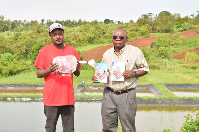 Two men standing in front of a pond.