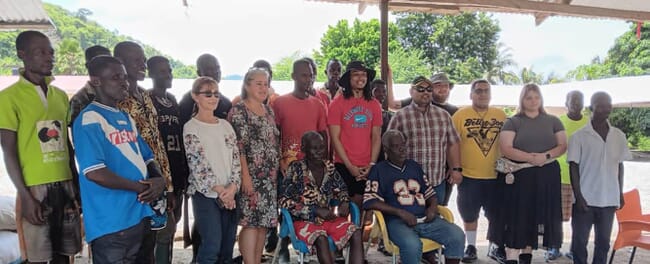 A group of people standing near a fish farm.