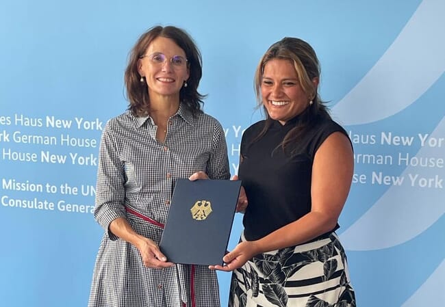 Two women shaking hands after signing an agreement.