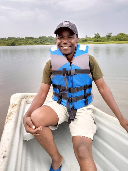 Man wearing a blue live vest, sitting in a boat