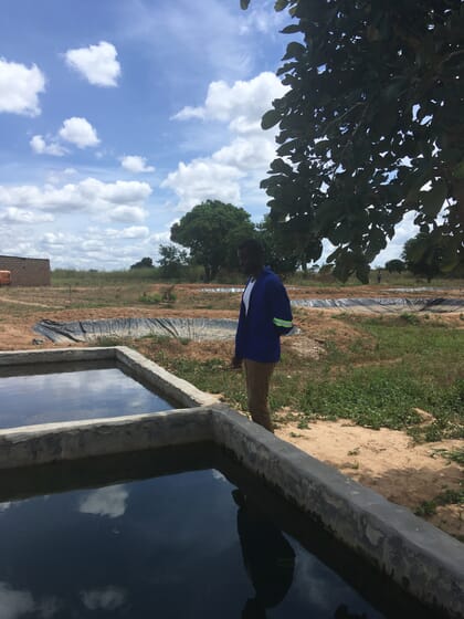 Man standing at the edge of two above-ground concrete ponds
