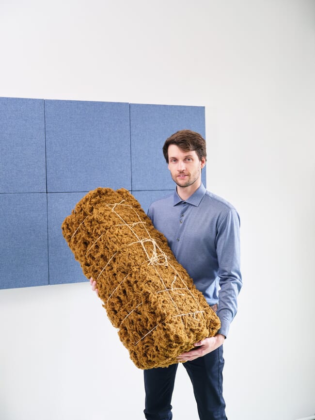 A man holding a bale of fabric.