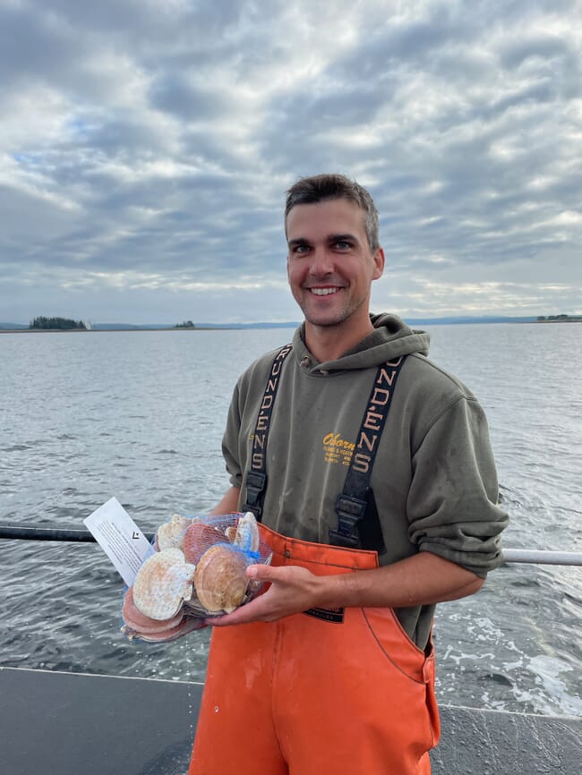 A man holding a bag of scallops.