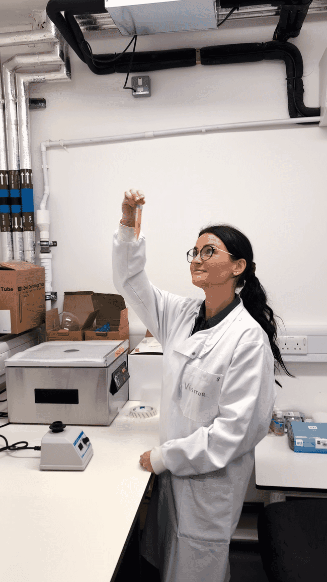 A woman in a lab coat examining a test tube.
